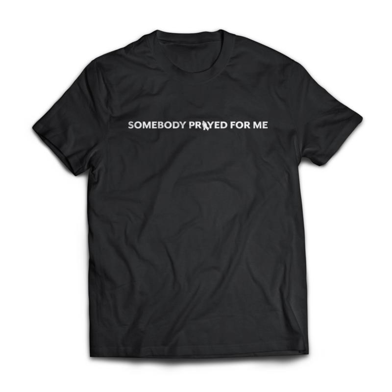 Black Christian t-shirt with white text reading “Somebody Prayed For Me” and praying hands design